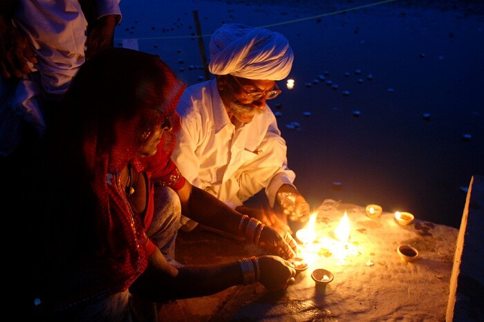 An elderly couple lights the diyas during the Kolayat Fair