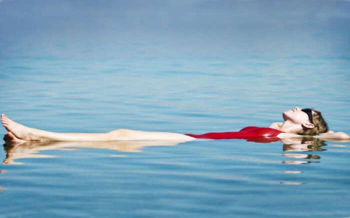 a lady wearing red swimsuit floating in Dead Sea