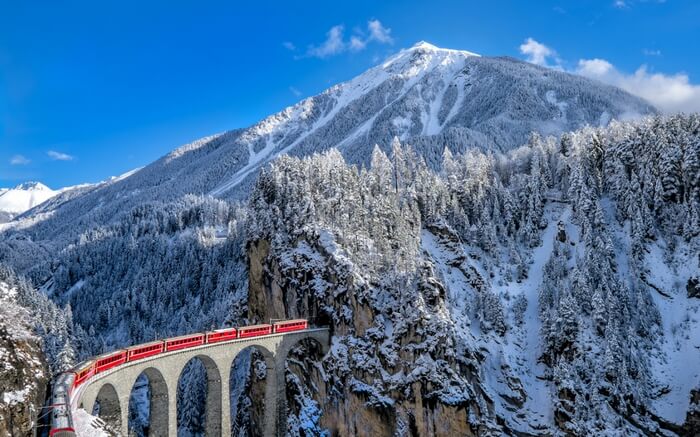 TheGlacier Express coming out of a tunnel in the Swiss Alps in Switzerland