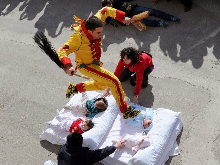 The exorcist hops over newborns during the baby jumping festival