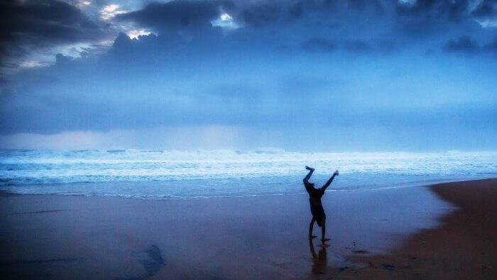 A boy doing a cartwheel at the beach