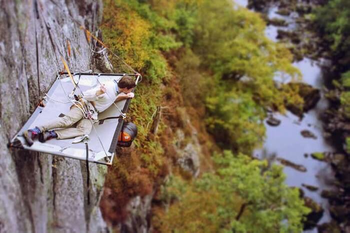 A man looking down the river stream while cliff camping