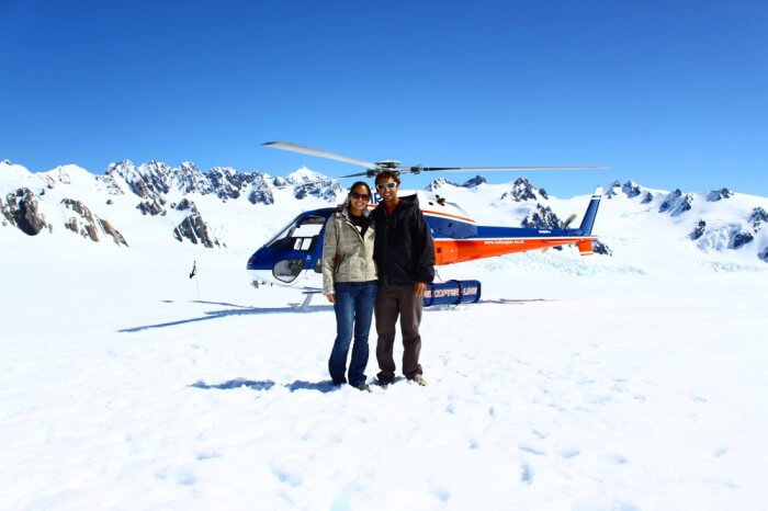 A couple poses with the helicopter used on the heli-hike at Fox Glacier