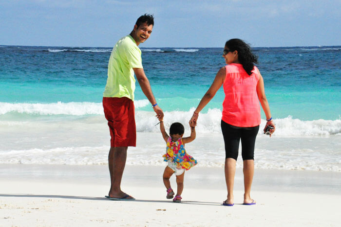 A couple walking on the shore with their tiny tot