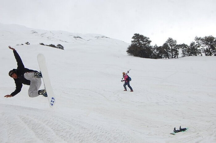 A tourist shows stunt with snowboard near Rohtang pass
