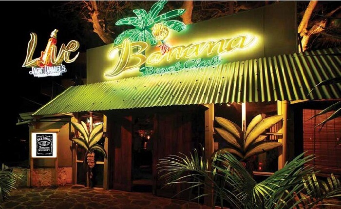 The glittering neon sign of Banana Beach Club attracts people to it