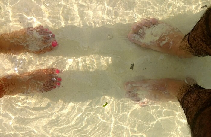 bhinav and his wife's feet immersed in water in Andaman