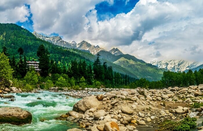 The flowing Beas river with the snow-capped hills in the backdrop at Manali