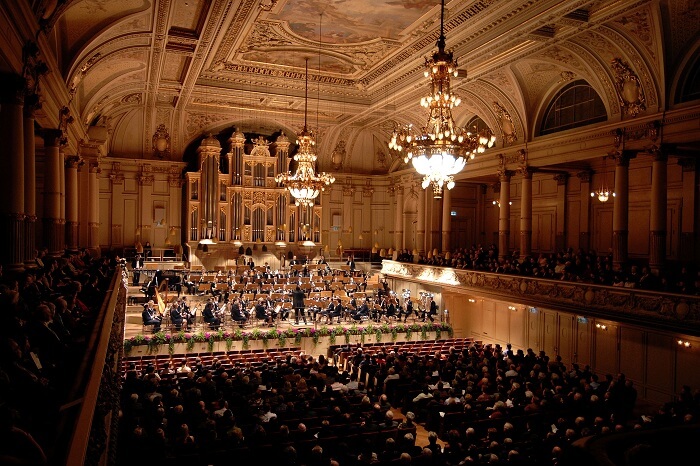 A vast audience attending a concert performed by 100 musicians at the Zurich Tonhalle