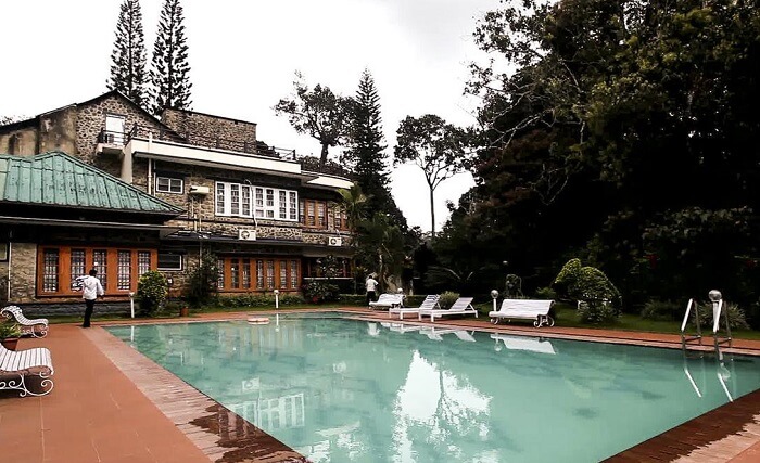 The pool-side area overlooking the victorian facade of Aranya Nivas Resort in Thekkady