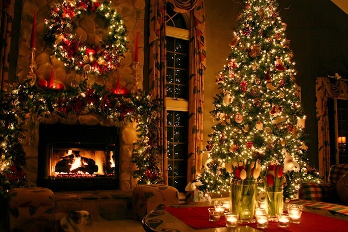 A shot of a decorated Christmas tree by the side of a fireplace in a house