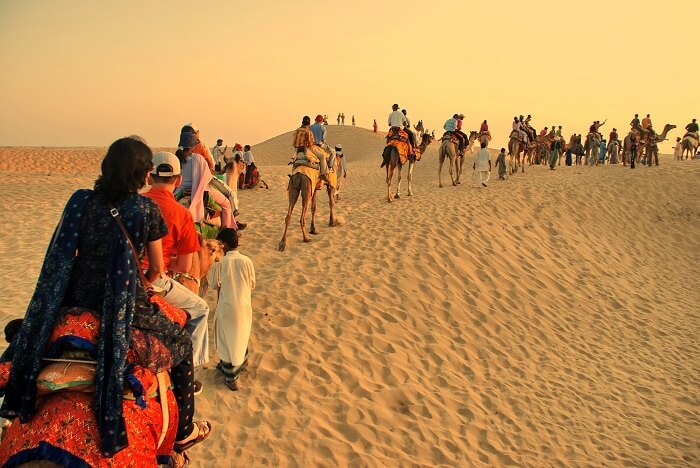 Happy tourists enjoying camel safari in Rajasthan