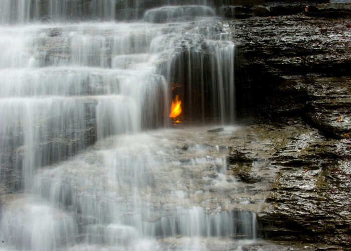 Mysterious eternal flame burning under the waterfall