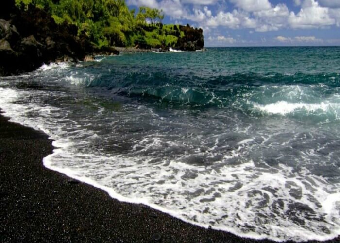 Have a view of the black sand amidst the crystal clear waters