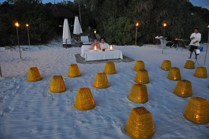 A couple being served barbecue dinner at a beach on Pamalican Island