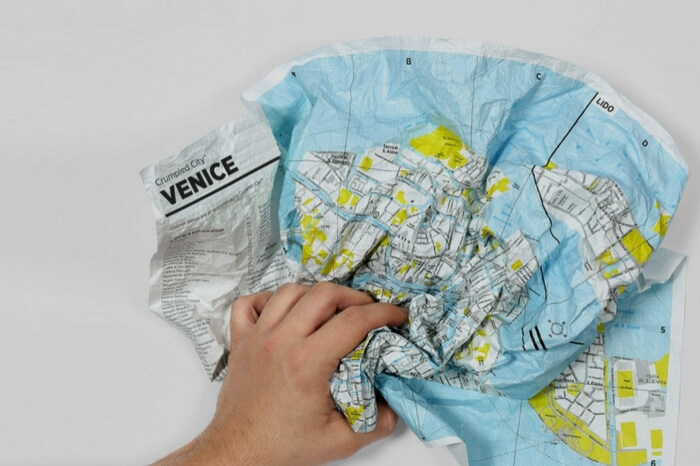 A crumbled waterproof map in a man’s hand