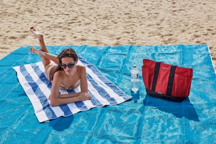 A woman sunbathing on a beach mat