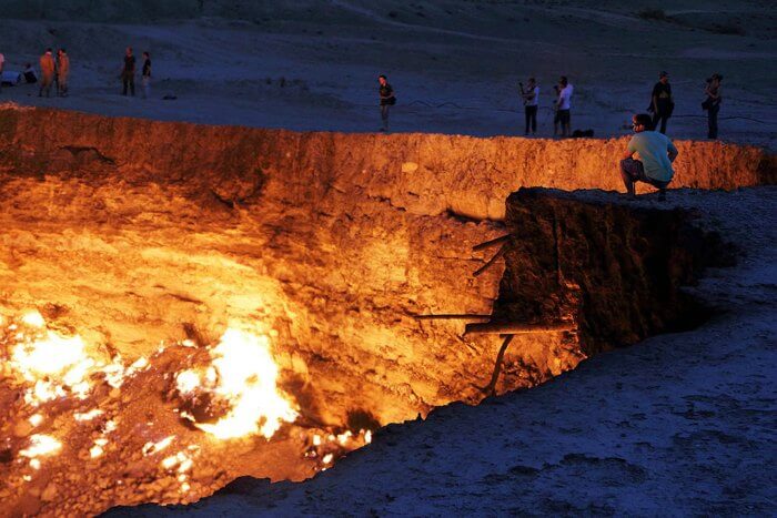 A man sitting on the edge of the Door to Hell in Turkmenistan