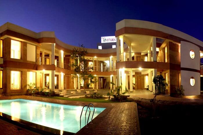 An evening shot of the swimming pool and the hotel building at the Chitvan Hotel in Ajmer