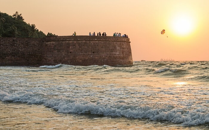 People looking at the sea while enjoying sunset from Aguada Fort in Goa which is one of the most popular forts of India