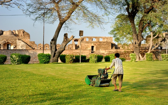 A gardener is cleaning lawn with mower in the Jhansi Fort