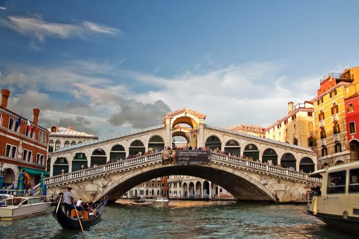 A boat sailing towards the arc of Rialto Bridge in Venice