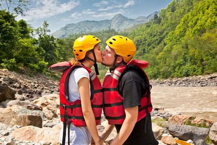 Man and woman kissing for good lack before river rafting during their honeymoon in Nepal