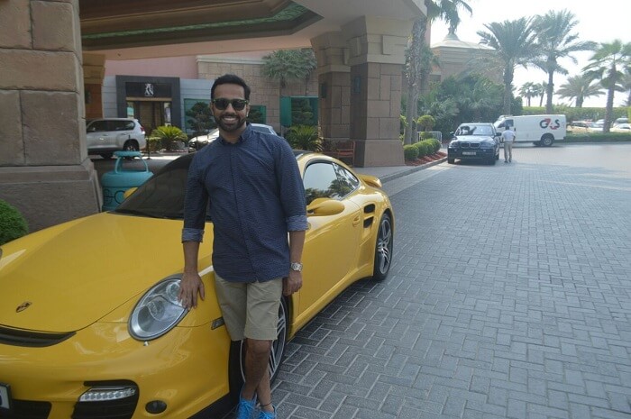 Man posing next to a yellow ferrari