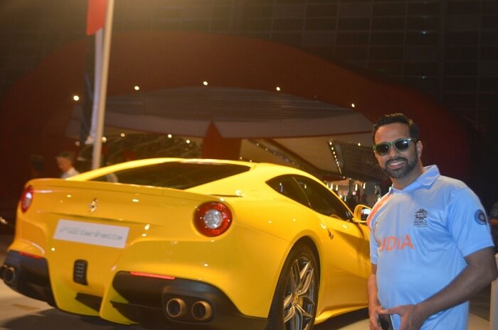 man posing next to a yellow ferrari