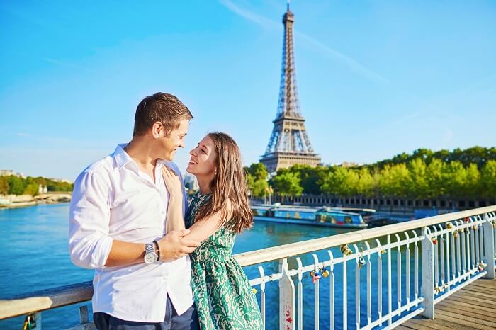 A couple on a bridge with the Eiffel Tower in the background