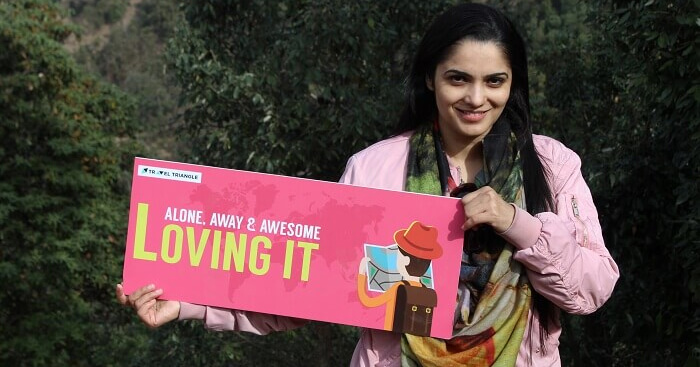 Vandana holding a banner and posing for a photograph during a family trip to Dhanaulti
