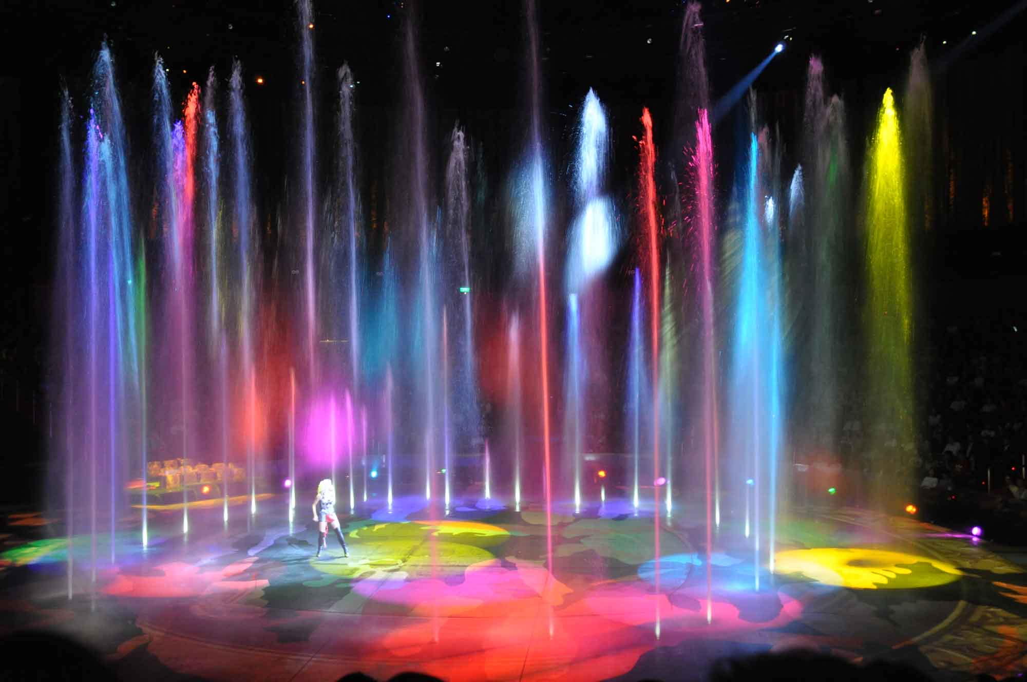 A lady performing solo in the middle of colorful water fountains