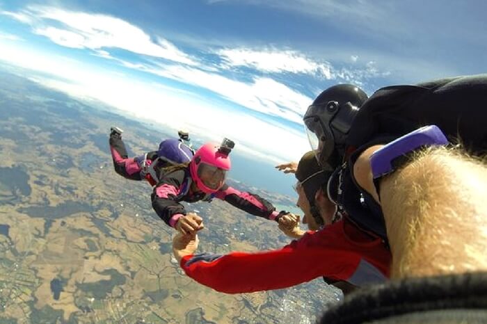 Skydivers playing mid air while taking up skydiving in the Bay of Islands area