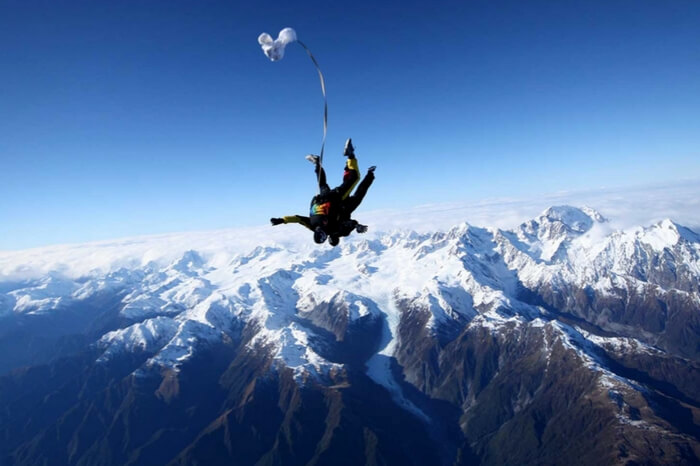 Skydivers during a freefall in the Fox Glacier region