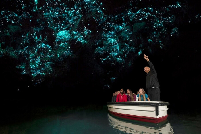 Travelers taking a tour of the Waitomo Glowworm Caves in New Zealand