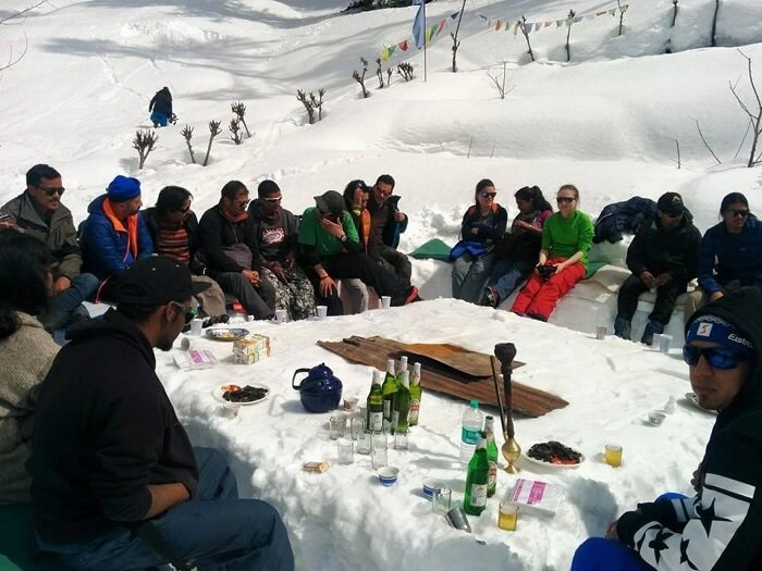 A group of campers having a meal outside the igloo in Manali