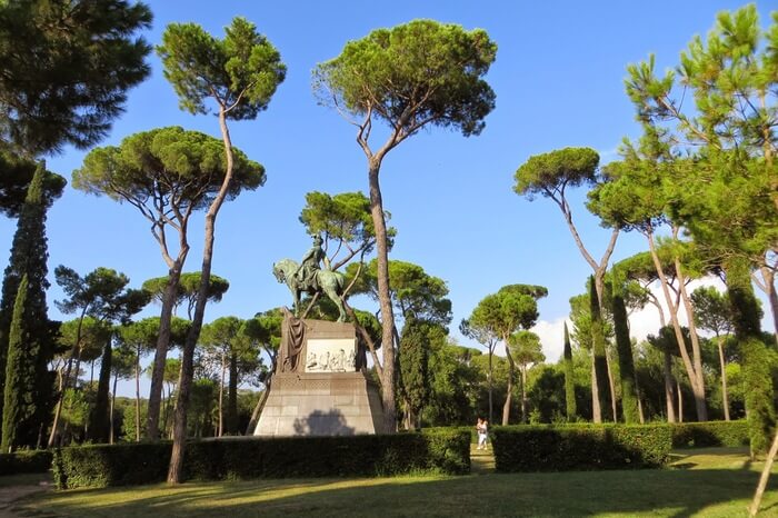 tall trees and a stone statue in a garden