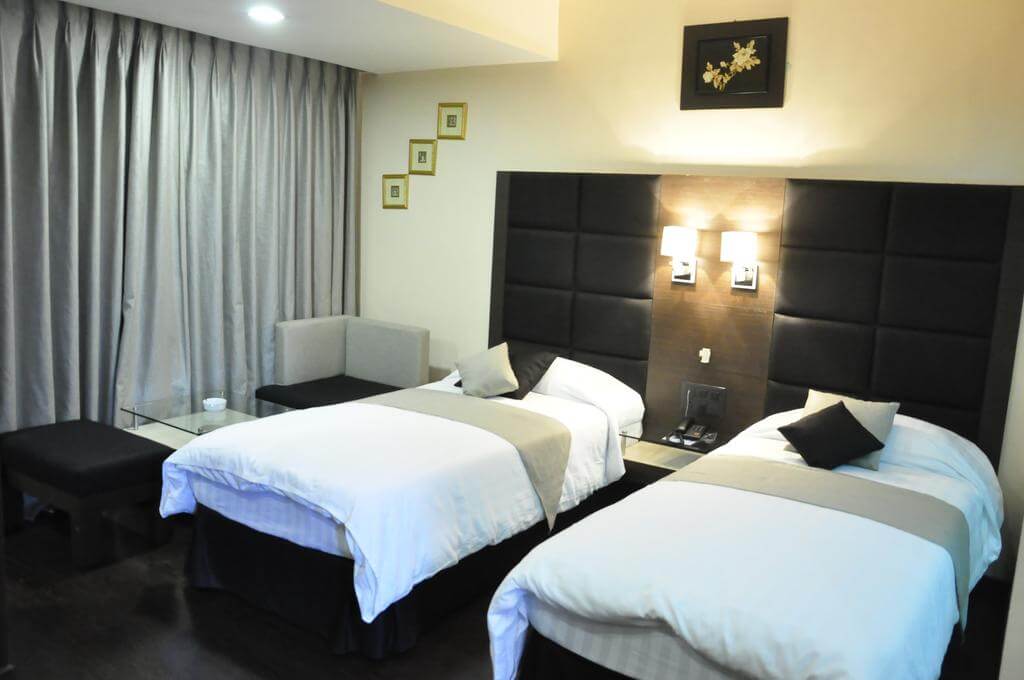 two luxurious beds with gray curtains in Hotel Alpine Continental