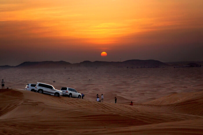 Travelers watching sunrise during desert safari in Dubai