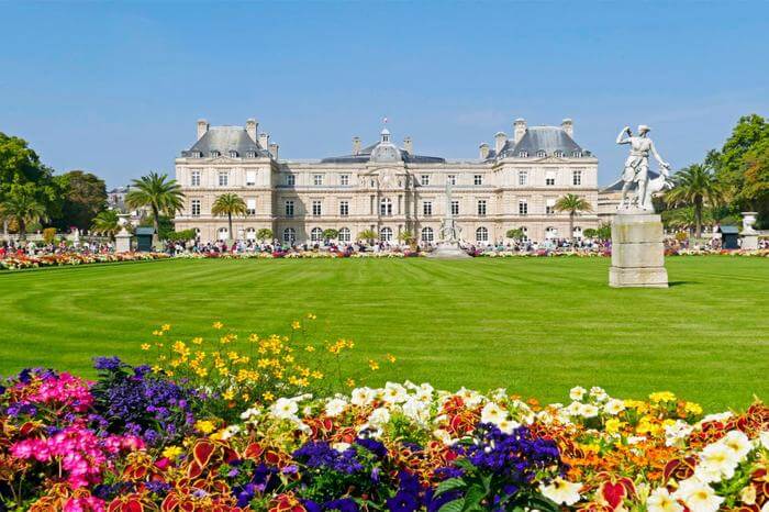 a grand palace in garden surrounded by flowers