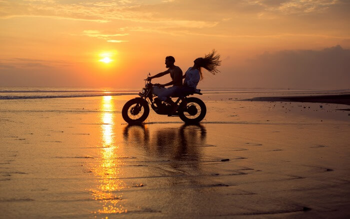 A couple biking on a beach in Bali