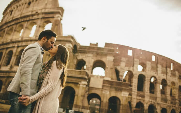 : A couple kissing in front of Colosseum