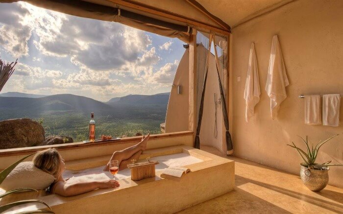 A woman enjoying a drink and scenery from her bathtub in Saruni Samburu in Kenya