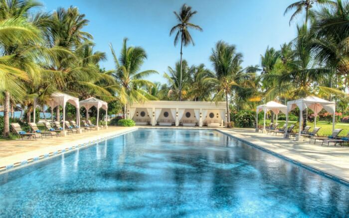 an open pool in a resort with palm trees around it