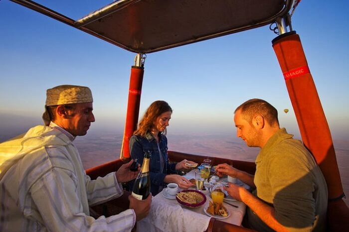 A couple dining in a hot air balloon flying over the Sahara Desert in Morocco