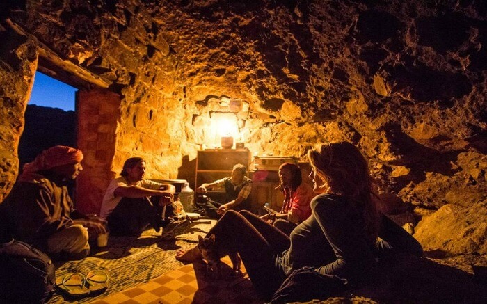 tourists living inside a dimly lit cave with Bedouin people