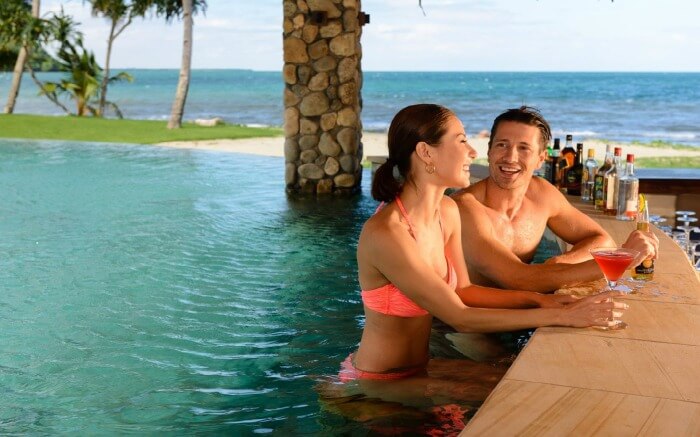 A couple relaxing on a beach by the ocean in Nanuku Resort and Spa in Fiji