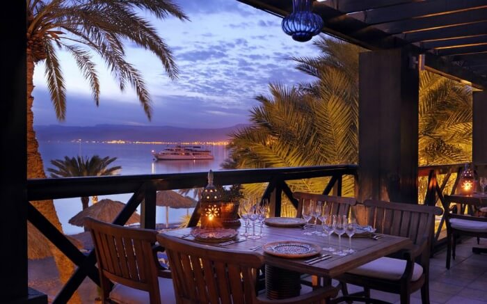 A dining table with empty wine glasses overlooking the Read Sea