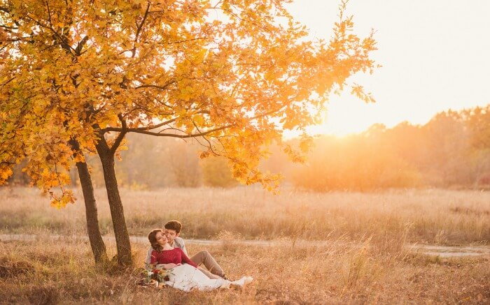 Couple romancing under a maple tree in autumn