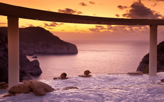 Couple spending leisure moments in an infinity pool at the time of sunset in Spain